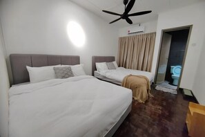 A hotel room with two beds, a ceiling fan, a bathroom with a toilet, and a door leading to another room.