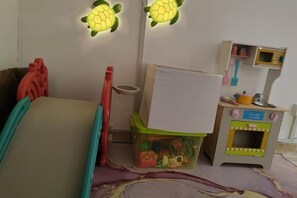 Un espace de jeux pour enfants avec un coin cuisine miniature, un réfrigérateur miniature et un lave-linge miniature.
