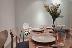 A dining table set with plates, cutlery, and a vase of flowers. - Damansara Jaya Petaling Jaya 2 Storey Landed House for 15 Pax (Petaling Jaya)