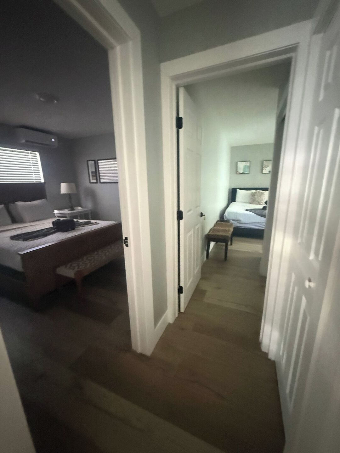 A hotel hallway with a bed, bedside table, and lamp in the room.