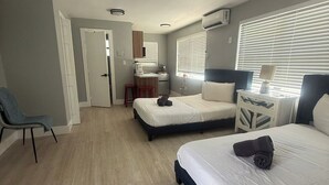 A modern hotel room with two beds, a small kitchenette, a bathroom, and a seating area. - Dania Beach Getaway 2 Studios for 6 Guests (Hollywood)