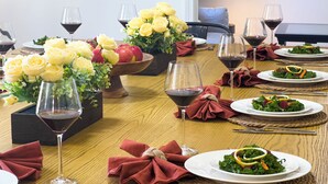 Et spisebord dækket med flere tallerkener mad, vinglas og en vase med gule roser.