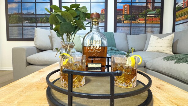 Et barområde med en whiskyflaske, glas og en bakke på et træbord.