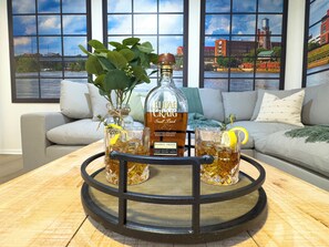 A bar area with a bottle of whiskey, glasses, and a tray on a wooden table. - Columbus Quarters (Columbus)