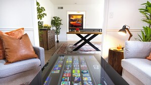 En moderne stue med et glasbord, der viser forskellige app-ikoner, en bænk og en lampe.