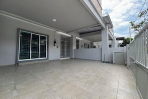 An empty indoor space with a tiled floor, large sliding glass doors, and a metal fence. - Langkawi Cozy Holiday Home at Taman Simfoni by Zervin (Langkawi)