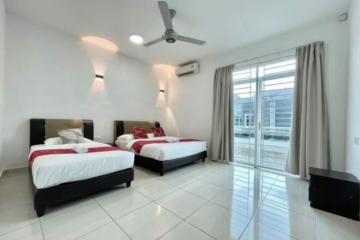 Ein Hotelzimmer mit zwei Betten, einem Deckenventilator, einer Klimaanlage und einer großen Glasschiebetür nach draußen.