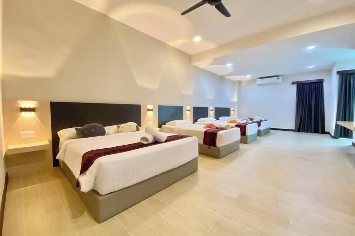 Ein Hotelzimmer mit drei Betten, einem Deckenventilator, Einbaustrahler und einem großen Fenster.