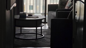 Une chambre avec vue sur l’océan, un balcon avec une balustrade, un canapé, une petite table et un réfrigérateur.