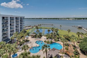 A resort with a pool area, tennis courts, and a view of the water. - Pelican Breeze 702A - 1BR Condo Overlooking the Gulf - Pool, Beach! (Gulf Shores)