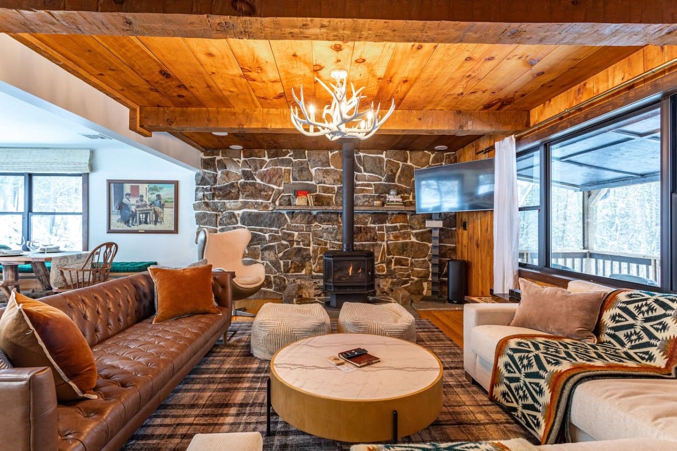 A cozy living room with a stone fireplace, leather sofa, and a large window.