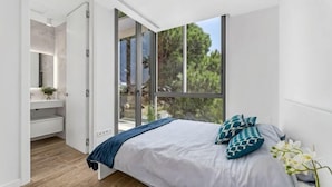 Un dormitorio con cama, mesita de noche, ventana y baño con lavabo y espejo.