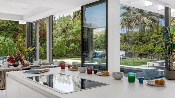 Una cocina moderna con una isla grande, ventanas amplias y vistas a un jardín exuberante.