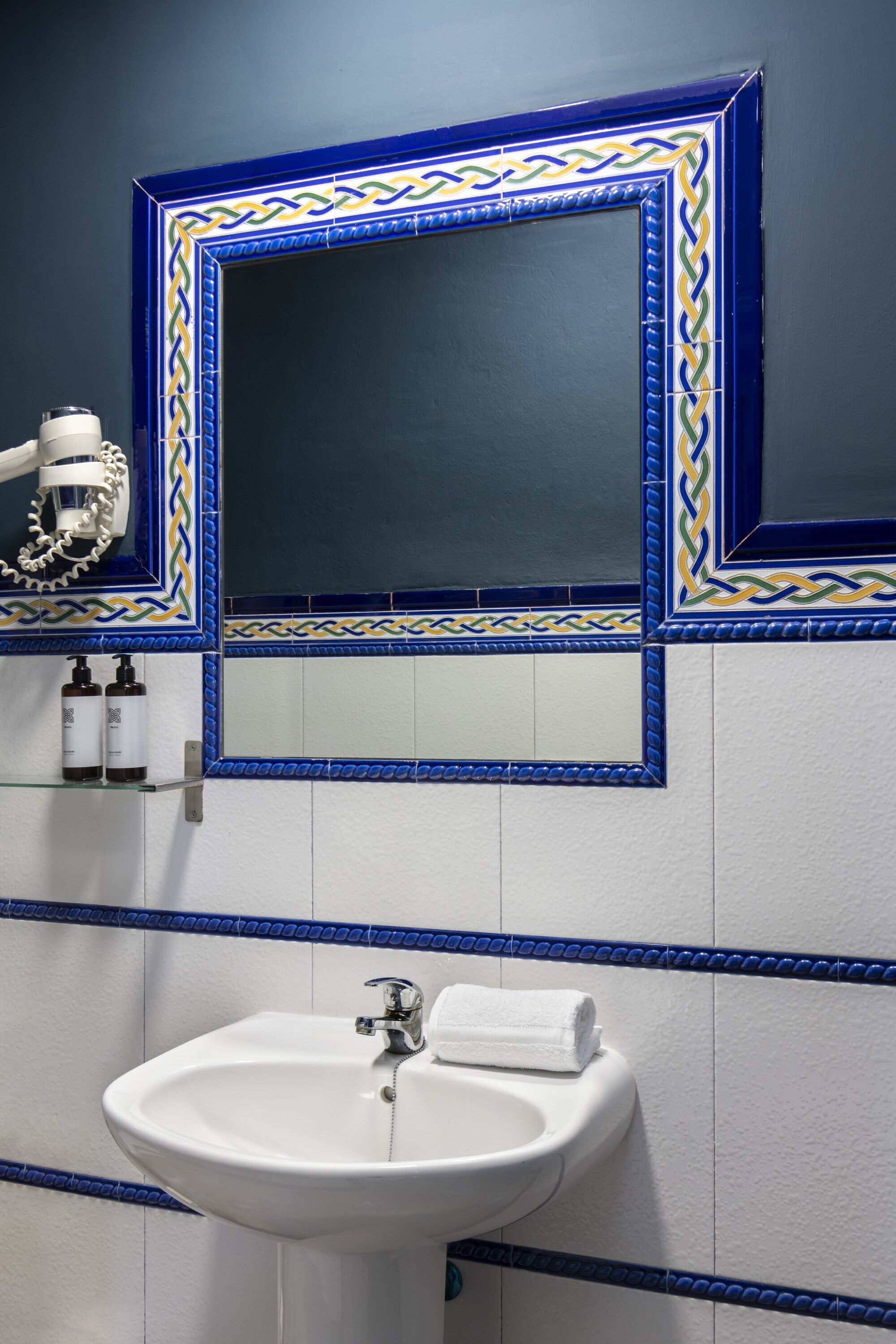 Um banheiro com uma pia branca, um espelho com moldura decorativa e uma toalha sobre a pia.