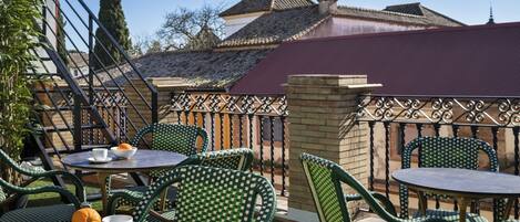 Una terraza con mesas al aire libre, vista a edificios tradicionales y cielo despejado.