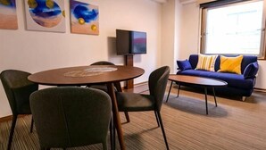 A room with a round table, chairs, a sofa, a flat-screen TV, and artwork on the wall. - J-Court Oshiage (Tokyo)