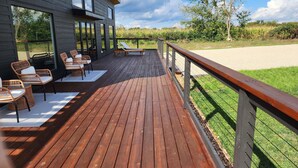 A wooden deck with outdoor furniture, a railing, and a view of the surrounding landscape. - Secluded Modern Cabin with Bluff Views, Hot Tub, Fire Pit. (Houston)