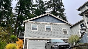 Ein zweistöckiges Haus mit Garage, umgeben von Bäumen und einer Auffahrt.