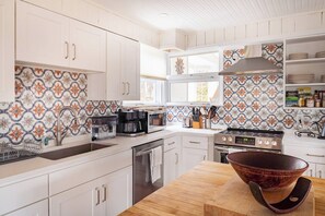 A modern kitchen with white cabinetry, a wooden countertop, and a large stove.