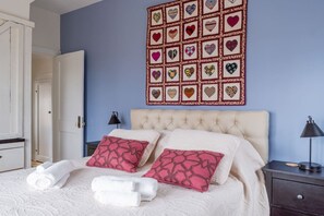 A bedroom with a bed, pillows, a wall art piece, and a nightstand. - The Ridge House: Hot Tub, Fireplace, WiFi, Deck (Saugerties)