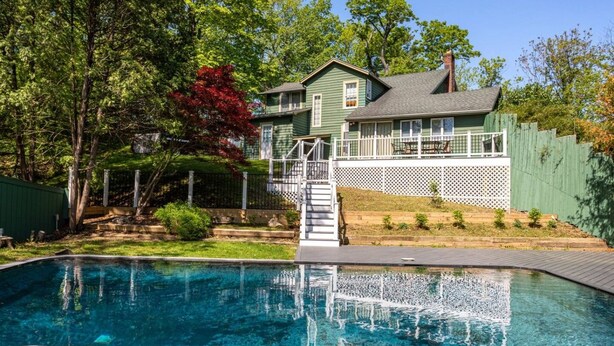Une propriété résidentielle dotée d’une piscine, d’une terrasse couverte et d’un jardin clôturé.