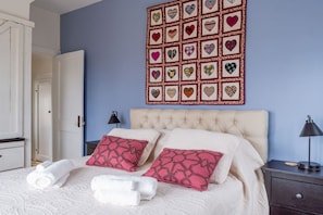 A bedroom with a bed, pillows, a wall art piece, and a nightstand.