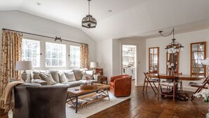Un salon spacieux avec un grand canapé, une table basse et un coin repas comprenant des chaises et une table en bois.