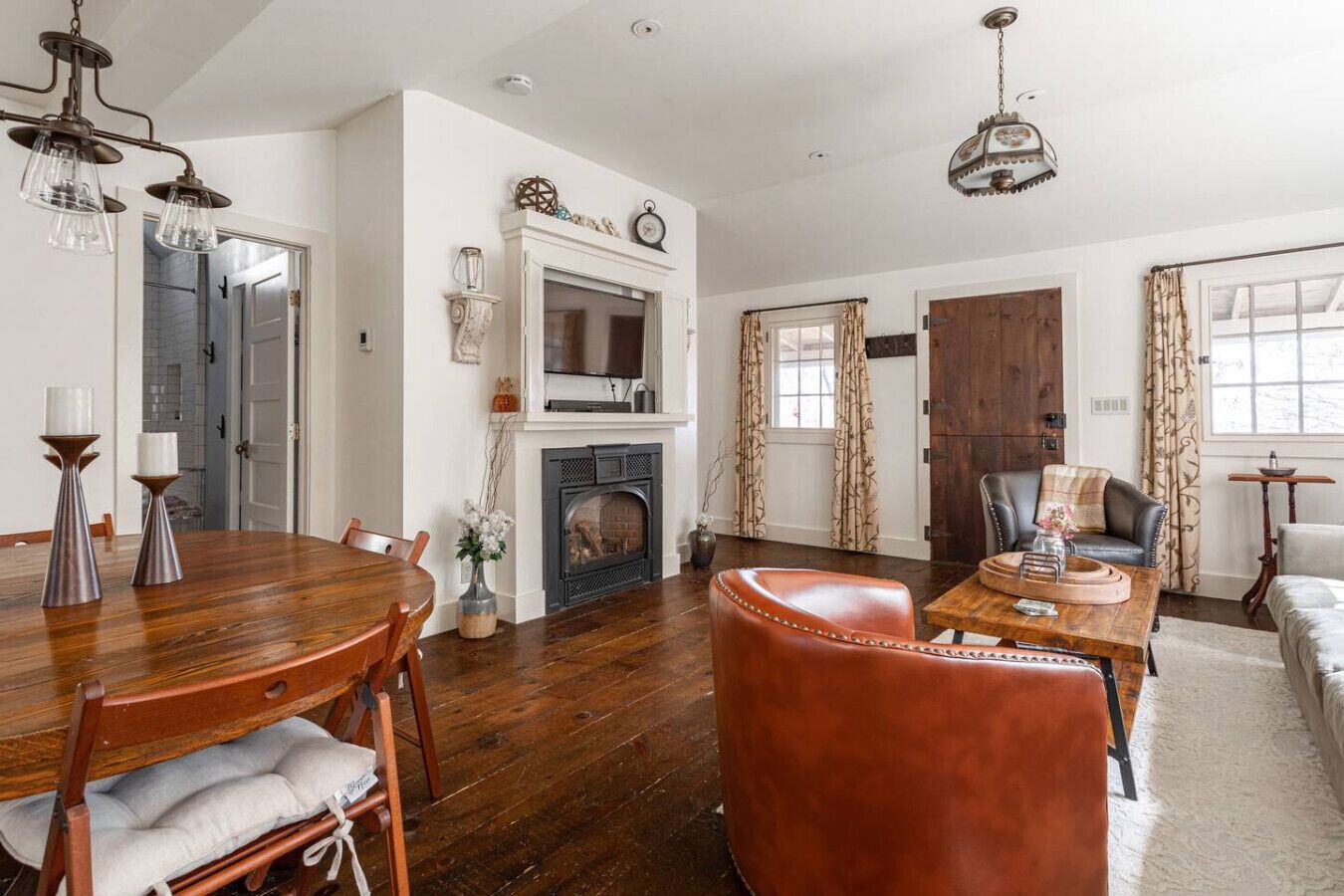 A spacious living room with a fireplace, a dining area with a wooden table and chairs, and a cozy seating area with a sofa and armchairs.