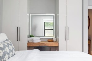 Una camera da letto con un letto, un comodino in legno, uno specchio e una finestra.