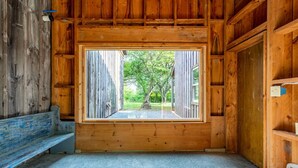 L’intérieur d’une cabane en bois, avec une grande fenêtre, un banc et une porte.