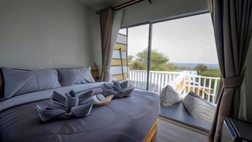 A bedroom with a large bed, a balcony with a view, and a window with curtains.