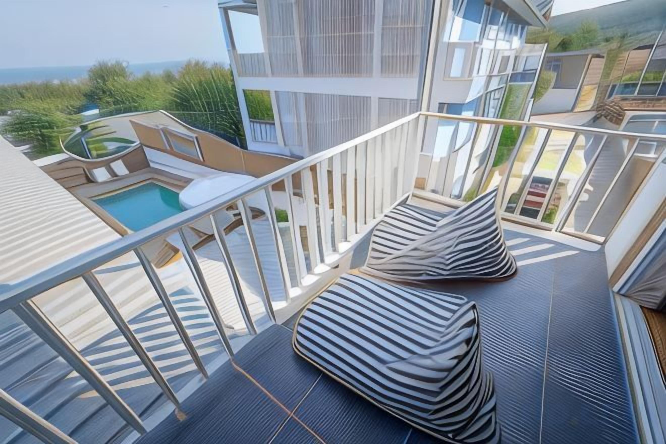 A balcony with a pool, outdoor seating, and a view of the sea.