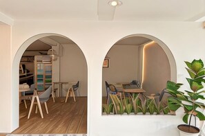 A room with a wooden floor, a dining table with chairs, and a potted plant. - Le Soleil Koh Larn (Koh Larn)