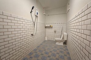 A small, tiled bathroom with a toilet, a hand dryer, and a paper towel dispenser.
