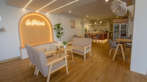 A modern interior with a wooden floor, a neon sign reading "le Solal", and a dining area with a refrigerator and bar. - Le Soleil Koh Larn (Koh Larn)