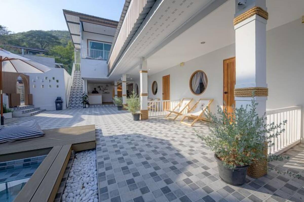 A modern outdoor patio with a pool, seating areas, and potted plants.