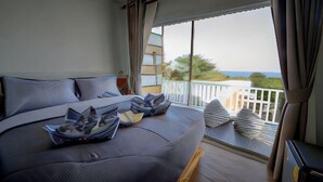 A bedroom with a large bed, a balcony with a view, and a sliding door. - Le Soleil Koh Larn (Koh Larn)