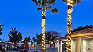 A patio area with a fire pit, outdoor seating, and palm trees. - Desert Dream Airstream with Pool (Yucca Valley)