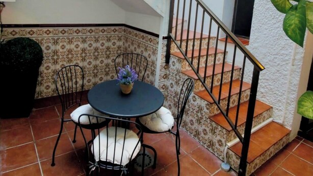Une terrasse avec une table ronde et des chaises, un escalier et des guirlandes lumineuses.