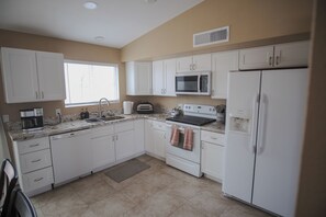 A kitchen with white cabinets, a microwave, a refrigerator, a stove, and a sink. - Desert Oasis: Near I-10, Basketball Court + Gym (Tucson)