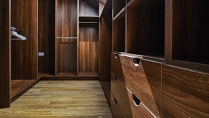 Un dressing accessible sans porte, avec des étagères et des tiroirs en bois, une lucarne et un plancher en bois.