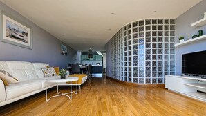 Un salon moderne avec un canapé blanc, une table basse et un meuble pour la télévision.