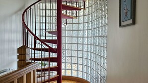 Un escalier en bois avec une rampe rouge menant à l’étage supérieur.
