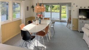 En matplats med ett vitt bord, flätade stolar och en vas med blommor.