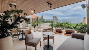 An outdoor patio with seating, tables, and potted plants. - Lomm By Somos The Group (Medellín)