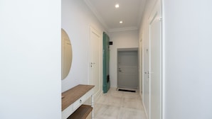 A hallway with white walls, a wooden bench, and a door with a green frame. - Toompea Castle 2 BR Old Town Apartment (Tallinn)