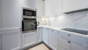 A modern kitchen with white cabinetry, a built-in oven, a microwave, and a marble backsplash. - Toompea Castle 2 BR Old Town Apartment (Tallinn)