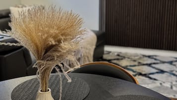 Un salon moderne avec un vase décoratif posé sur une table noire, un canapé et un téléviseur fixé au mur.