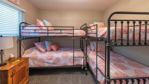A bunk bed room with a wooden nightstand, a lamp, and a framed picture on the wall. - Beach Bum Retreat (Cayucos)