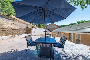 A patio with a table and chairs, an umbrella, and a stone wall. - Red River Retreat (Paso Robles)